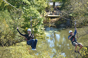 Two people zip line together at Lake Erie Canopy Tours